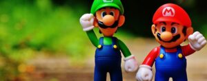 Figurines of Mario and Luigi celebrating teamwork, symbolizing cross-training and collaborative competence in a medical device QMS training program.