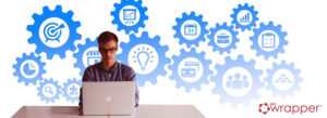 A professional working on a laptop with a background of blue gear icons containing symbols for goals, planning, teamwork, and data, representing the integrated phases of the medical device lifecycle.