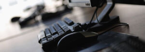 Close-up of a developer's workstation with a keyboard and monitor, representing the use of qmsWrapper’s integrated chat to capture real-time firmware development logs for DHF and QSR compliance.