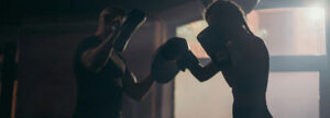 Two people boxing in a gym, representing the conflict between different QMS experts and the challenge of filtering conflicting advice for medical device quality management.