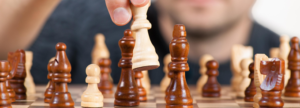 Hand moving a chess piece on a board, symbolizing strategic planning for medical device ISO 13485:2016 and FDA QMSR compliance in 2026.
